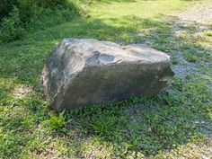 a large rock sitting on top of a lush green field