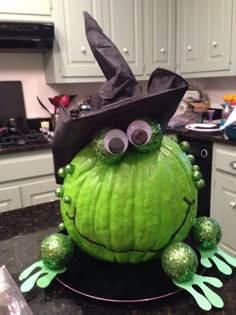 a green pumpkin with googly eyes and a witches hat