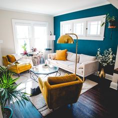 a living room filled with furniture and lots of plants on top of the tables in front of them