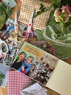 the table is covered with many different items such as scissors, cards and flowers in vases