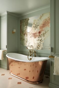 a bathtub in a bathroom with green walls and gold fixtures on the tub side