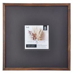 a wooden frame with a black and white photo in the bottom right corner is an image of a dried plant