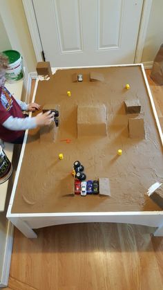 a young boy is playing with his toys on the floor in front of a table