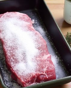 a raw piece of meat in a pan with powdered sugar on the top and sprinkles around it