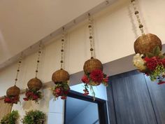 several hanging baskets filled with flowers and greenery on the wall next to a mirror