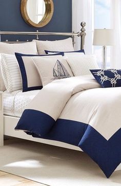 a bed with blue and white comforters in a bedroom next to a mirror on the wall