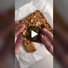 a person holding a cookie in front of a piece of food on top of paper