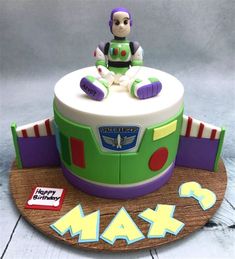 a birthday cake with a toy sitting on top of it that says happy birthday max