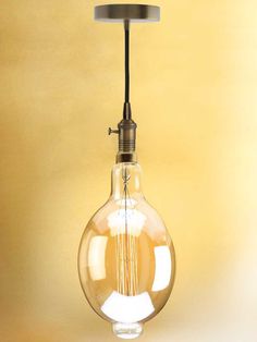 an old fashioned light bulb hanging from a metal ceiling fixture on a yellow painted wall