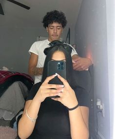 a woman taking a selfie in front of a mirror with a man behind her