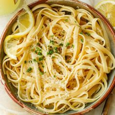 a bowl full of pasta with lemons and parmesan cheese on the side