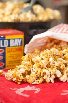 a bag full of popcorn sitting next to a container of old bay seasoning on a table