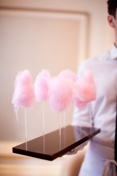 pink cotton candy lollipops sitting on a tray with a person in the background