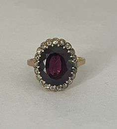 Yellow gold (18k) ring holding an oval faceted Almandine garnet of approximately 6.50 ct (13.6 x 11.5 x 5.4 mm) in a setting of 22 old-cut diamonds. Total weight of diamonds: approximately 0.45 ct. Tray: 20 x 15 mm. Gross Weight: 5.30 g. Size: 55.5 Possibility of sizing, contact us. Further information : We issue an invoice as well as a certificate of authenticity established by our qualified gemologist (LFG Paris). Our photos are not reworked and are taken in a natural light environment. We can Collectible Oval Ruby Ring With Diamonds, Antique Oval Ruby Ring, Elegant Oval Ruby Ring With Rose Cut Diamonds, Oval Ruby Ring With Diamond For Collectors, Oval Ruby Ring With Rose Cut Diamonds, Antique Oval Diamond Ring For Formal Occasions, Vintage Oval Ruby Ring With Halo Setting, Victorian Oval Diamond Ring With Center Stone, Formal Oval Ruby Ring With Single Cut Diamonds