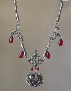 This beautiful necklace showcases beautiful beads of different types and intricate silver detailing. The center piece is the silver heart/ornamental part in the middle. This is one of the most beautiful vampire inspired jewelry pieces I have made, inspired by my own fantasy creativity. None of the metal in this is real and will rust if exposed to water. I recommend taking it off when you sleep. Silver Vampire Style Necklace, Gothic Metal Heart Necklace, Gothic Heart Pendant Necklace, Gothic Heart Necklaces With Heart Charm, Gothic Metal Heart Necklace For Valentine's Day, Silver Gothic Heart Charm Necklace, Silver Gothic Necklace With Heart Charm, Silver Gothic Jewelry With Heart Charm, Gothic Metal Necklace With Heart Pendant