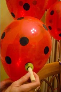 a ladybug balloon being held up by someone's hand