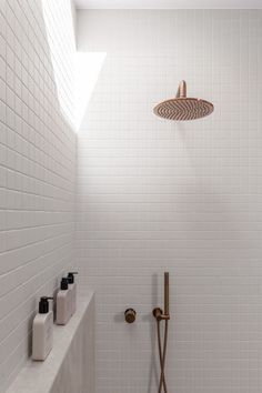 a white tiled bathroom with a shower head and hand held shower faucet in the corner