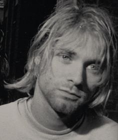 a man with long blonde hair wearing a t - shirt and looking at the camera