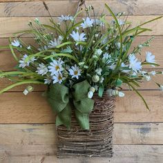 a basket filled with blue flowers sitting on top of a wooden floor next to a wall