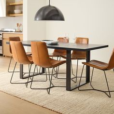 a dining table with six chairs and a black light hanging over it in the middle of a room