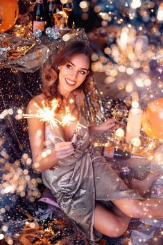 a woman sitting on the floor holding sparklers