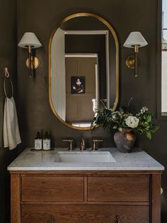 a bathroom with a sink, mirror and flowers on the counter in front of it