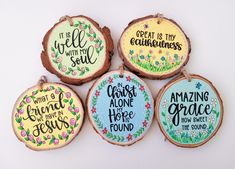 four wood slice ornaments with hand painted sayings on the front and back, each decorated in different colors