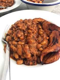 a white plate topped with baked beans and bacon