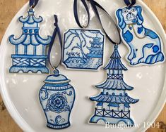 four ceramic ornaments on a white plate with blue trimmings and tags attached to them