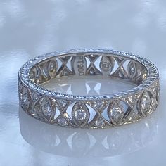 Details: Beautiful lacy delicate diamond and platinum eternity band. This band is super sparkly, and very feminine. The band is 4.4mm wide, with bead set diamonds with mill grain edging and hand engraved side profile. Every detail on this one is lovely. You'll be pleased to add this beauty to your collection. This ring comes with an appraisal. Appraisal Notes: Thirteen round brilliant diamonds measuring 1.6 x 1.6 x .96mm, approx. weight .19ct. Twenty-six round brilliant diamonds measuring 1.1 x Silver Platinum Eternity Band With Diamond Accents, Silver Eternity Band With Diamond Accents Fine Jewelry, Dazzling Platinum Eternity Band For Anniversary, Milgrain Eternity Band, Dazzling Platinum Eternity Band, Cameo Earrings, Side Profile, Bead Set, Lovely Ring