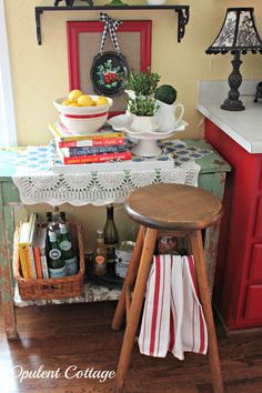 a small table with books and drinks on it in front of a red cabinet filled with other items