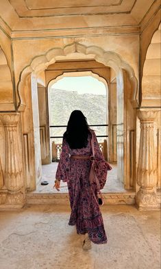 a woman in a long dress walking through an archway