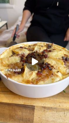 a person sitting in front of a pie on top of a wooden table next to a knife