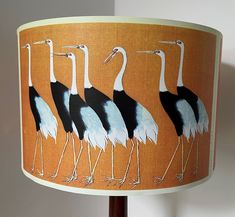 a lamp shade with four birds painted on the lampshade and one light is turned on