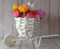 a basket with flowers in it sitting on top of a wooden table next to a roll of paper