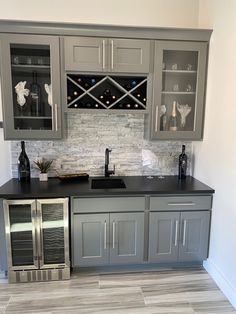 a kitchen with gray cabinets and wine bottles