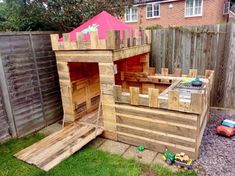 a child's play house made out of pallets and wooden planks in the back yard