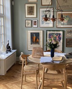 a dining room table with chairs and pictures on the wall in front of it's windows