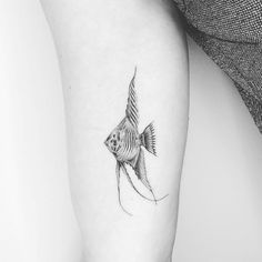 a black and white photo of a goldfish tattoo on the right arm, with its tail curled back