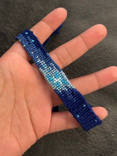 a hand is holding a blue beaded bracelet