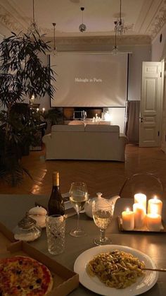 a table with pizza, wine and candles on it