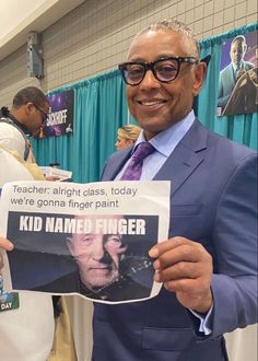 a man in a suit and tie holding up a sign that says kid named finger