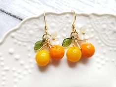 "glass orange drop earrings with cute white flower and green leaf Material: glass oranges, arcylic leaf and flower, gold plated hook drop length: about 1.25\" Contains small parts. Use caution when giving to young children less than Age 3 Please keep them away from moisture. If you have any questions, please feel free to contact me. Thanks :)" Purple Dangle Earrings, Earrings Food, Peach Earrings, Pear Earrings, Fruit Jewelry, Food Earrings, Fruit Earrings, Orange Earrings, Leaf Charms