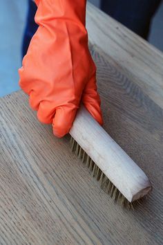 a person in orange gloves is cleaning a wooden table