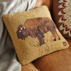 a brown bear pillow sitting on top of a couch next to a tan throw pillow