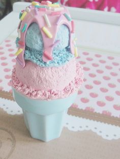 two ice cream cones with sprinkles and frosting on top sitting on a table