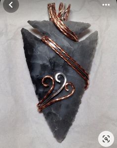 a piece of copper wire wrapped around a black rock with a spiral design on it