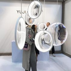 a woman standing in front of a display with large bubbles hanging from it's sides