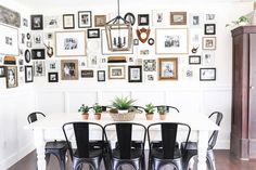 a dining room table with chairs and pictures on the wall above it, along with potted plants