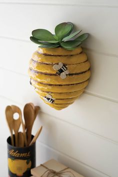 a yellow beehive hanging on the wall next to utensils